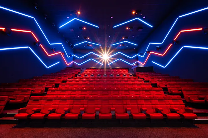 Foto, das den ULTIMATE. Saal mit roten Kinostühlen und blau-roter Beleuchtung des Cineplex Neufahrn zeigt