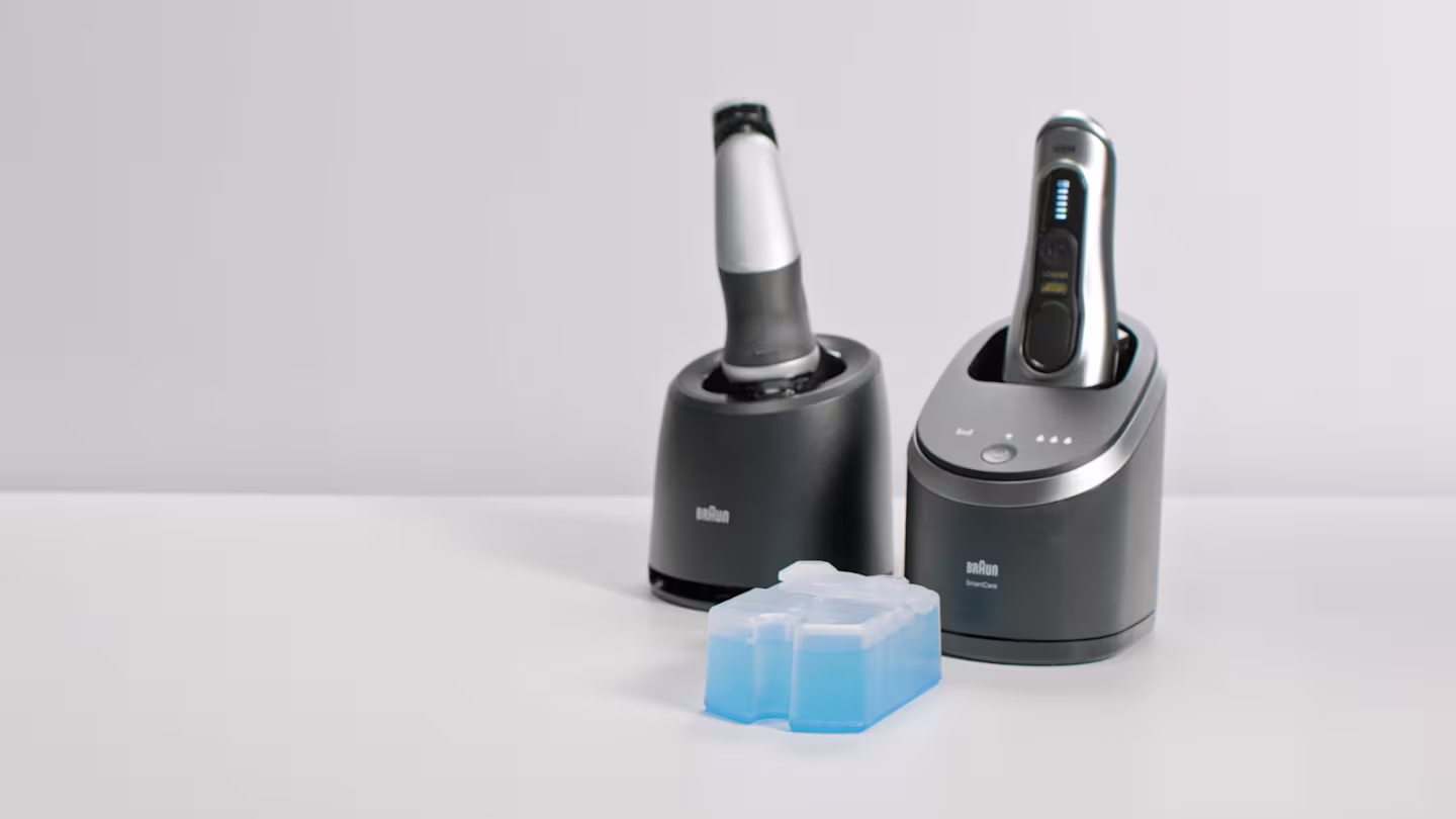 Braun electric shavers docked in their SmartCare stations and a cleaning cartridge.