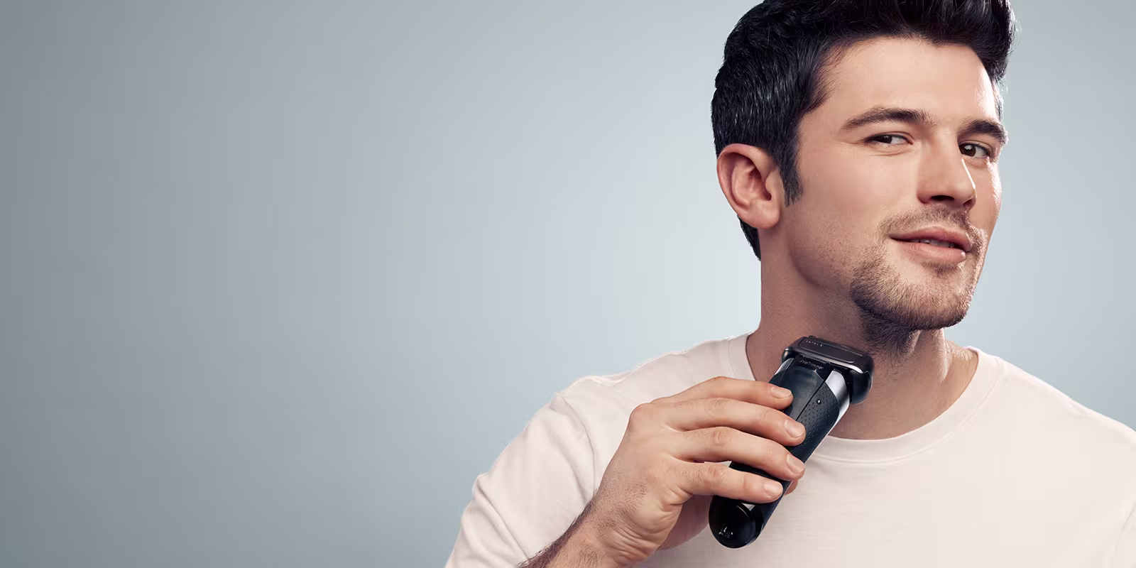 Man shaving his facial beard using a Braun Electric Shaver.