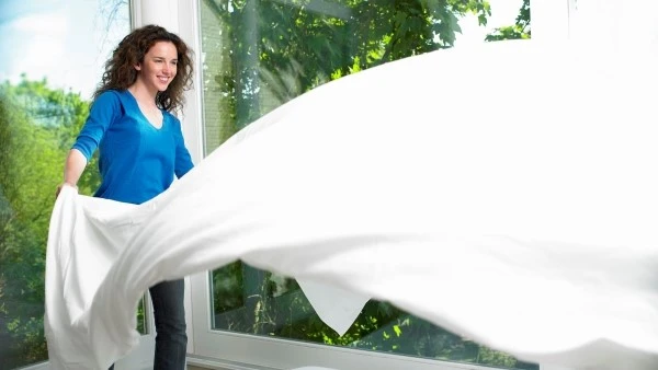 Девушка меняет постельное белье при аллергии на кошку