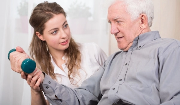 Девушка помогает пожилому мужчине выполнять упражнения