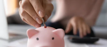 a person putting a coin into a piggy bank