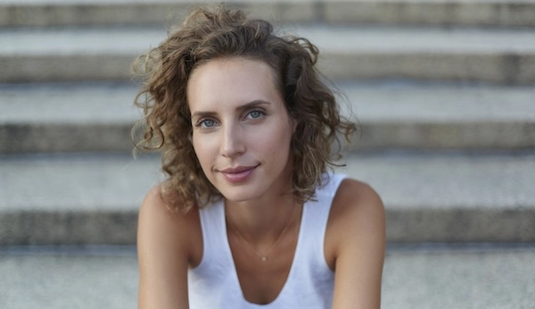 Голубоглазая девушка сидит на каменных ступенях