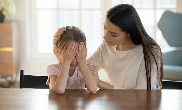 Девочка закрывает лицо руками, а мама ее успокаивает