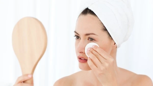 Завершающий этап промывания глаз — промакивание кожи ватным диском Девушка промакивает кожу под глазом ватным диском после промывания глаз