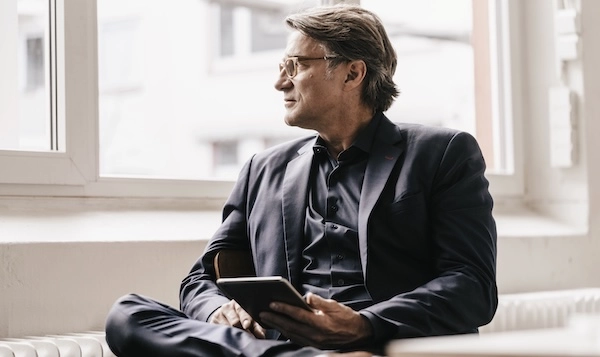 Мужчина с плохим зрением смотрит в окно Мужчина в очках смотрит в окно