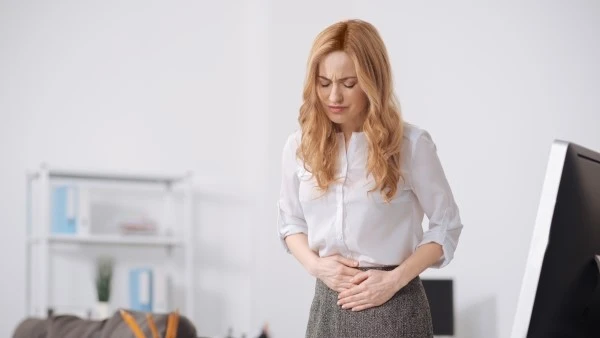 Девушка держится за живот при воспалительном заболевании кишечника