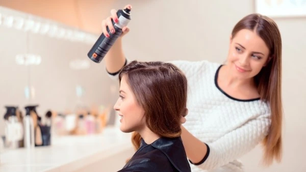 Агрессивное воздействие укладочных средств Стилист наносит укладочное средство девушке