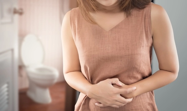 Подавление позывов к дефекации может провоцировать боли Женщина прикладывает руки к животу