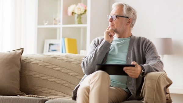 Задумчивый возрастной мужчина на диване