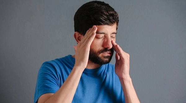 Мужчина касается виска и переносицы