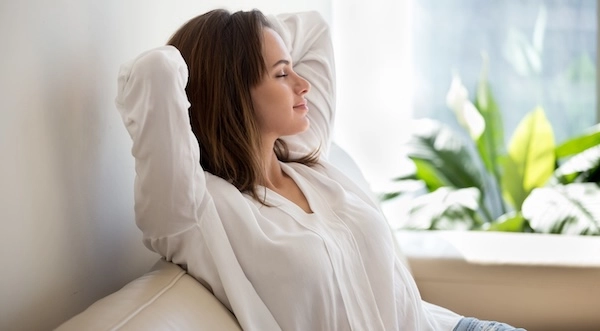 Девушка сидит на диване с закрытыми глазами