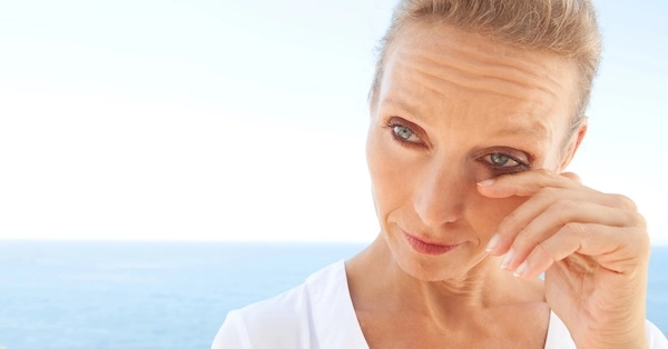 Женщина протирает глаз