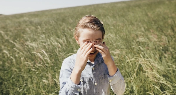 Девушка в поле держится за глаза
