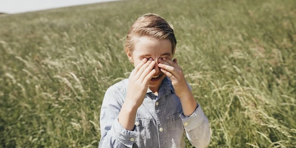 Девочка трёт глаза на фоне поля