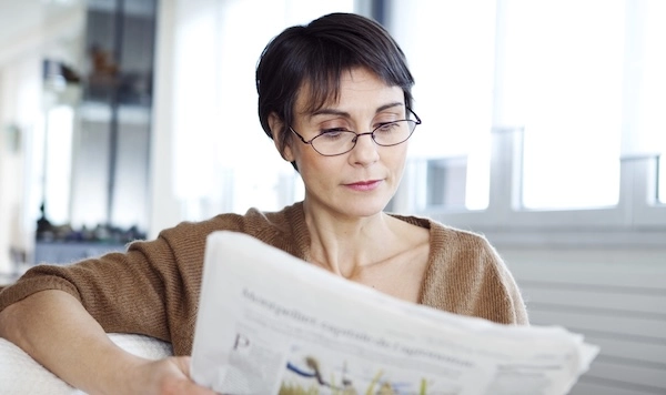 Женщина с плохим зрением читает газету Женщина в очках читает газету