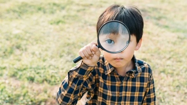 Мальчик приложил лупу к глазу