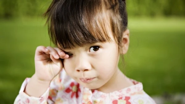 Девочка чешет закрытый глаз