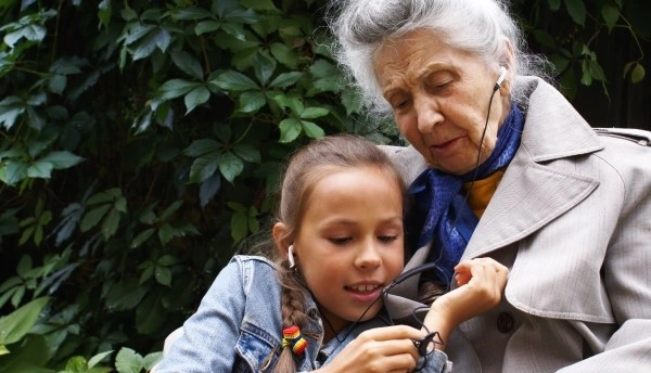 Длительное ношение наушников — фактор риска наружного отита у детей Девочка и бабушка вместе слушают музыку в наушниках