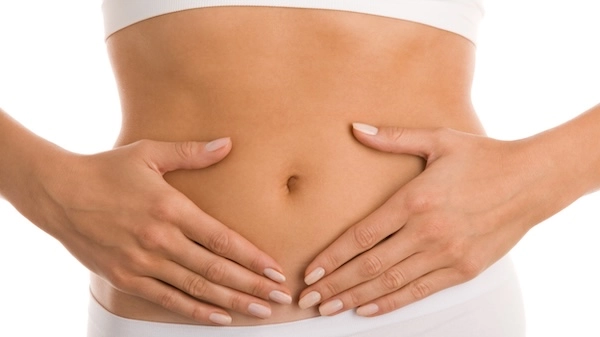 Девушка прикладывает руки к животу Девушка держит руки на животе