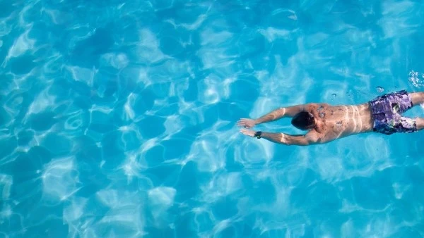 При холодовой аллергии купание в холодной воде может быть опасным Мужчина плавает в бассейне