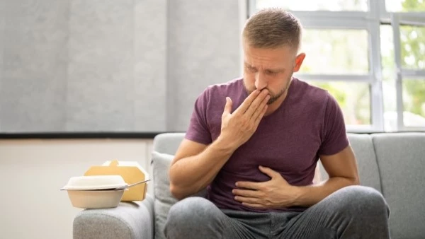 Тошнота при остром животе Мужчина прикрывает рот рукой и держится за живот