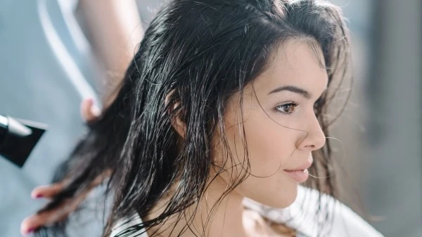 Длительное воздействие высоких температур может нарушить структуру волоса Девушке сушат волосы феном