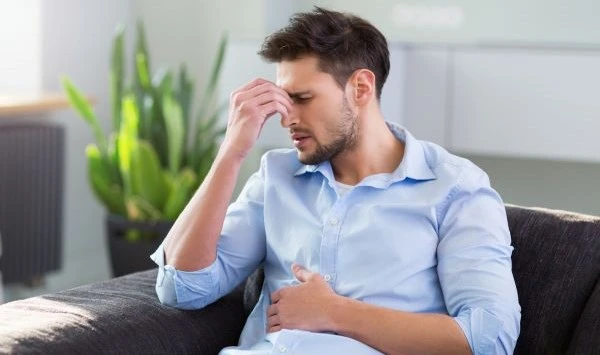 Мужчина держится за живот и испытывает боль