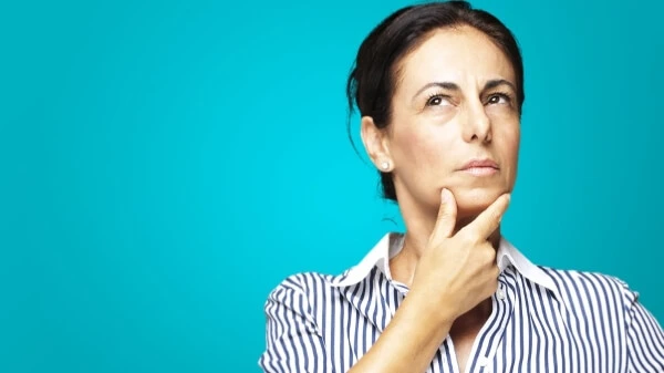 Женщина задумчиво касается подбородка, глядя в сторону