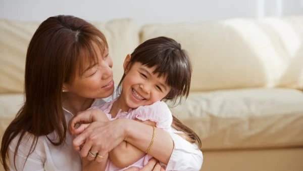 Мама обнимает смеющуюся девочку