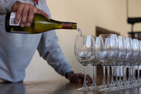 Person pouring wine into a row of glasses