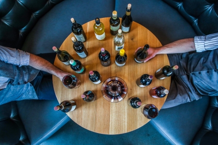 Aerial view of people sitting around table of bottles of wine