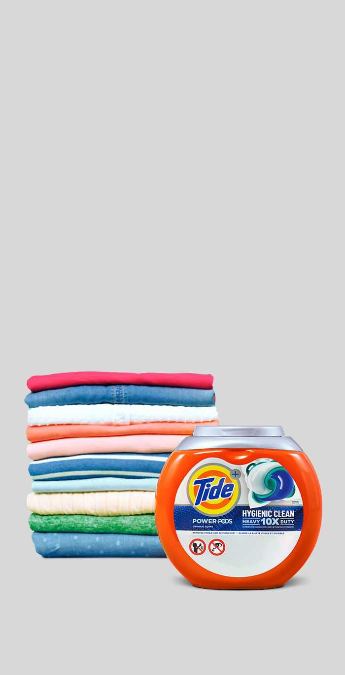 Tide Hygienic Clean Heavy Duty 10x Power PODS in front of a pile of folded colorful clothes