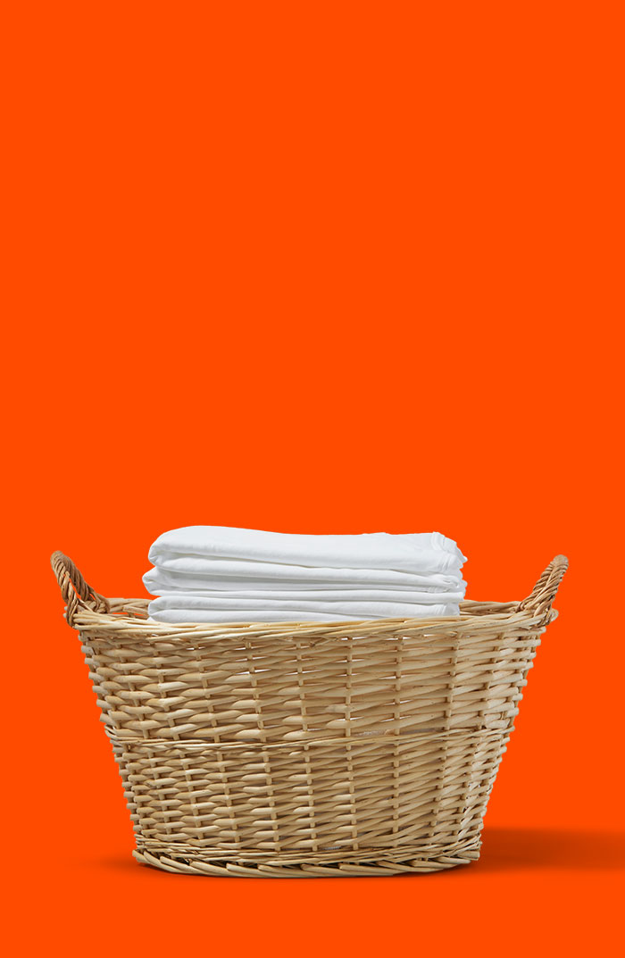 Folded white clothes in a woven laundry basket