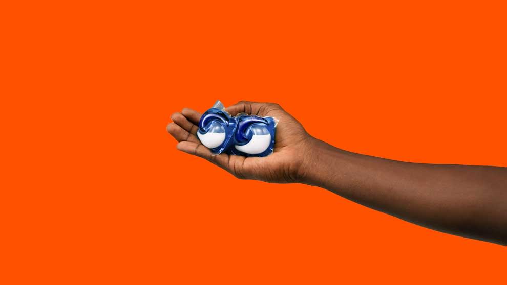 A person holding 2 Tide PODS washing capsules