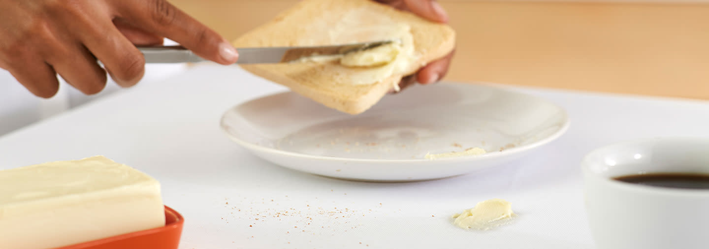 A person spreading butter on a slice of toast