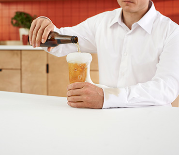 A person in a white shirt pouring beer into a glass