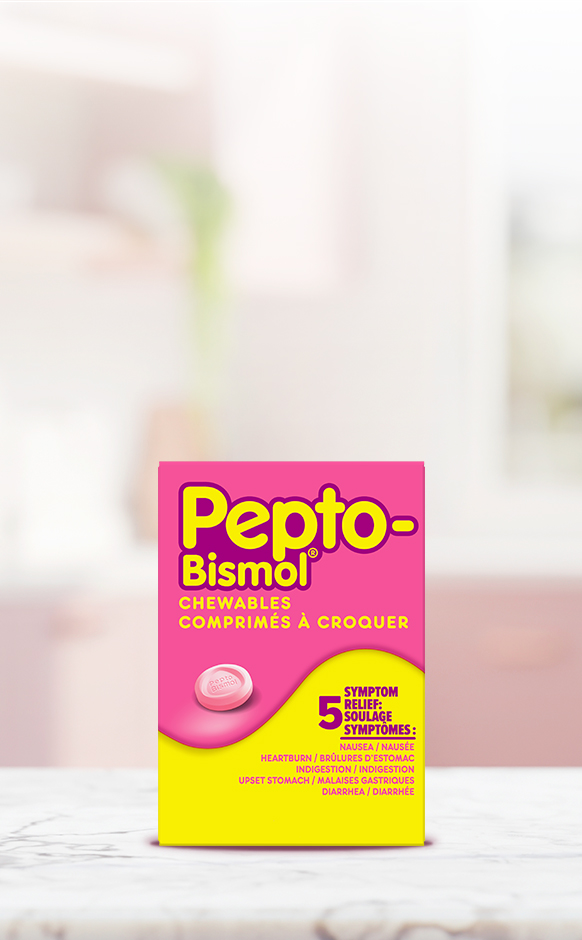 Pink and yellow Pepto-Bismol Chewables box providing 5-symptom relief, displayed on a marble surface with a blurred background.