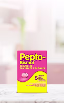 Pink and yellow Pepto-Bismol Chewables box providing 5-symptom relief, displayed on a marble surface with a blurred background.