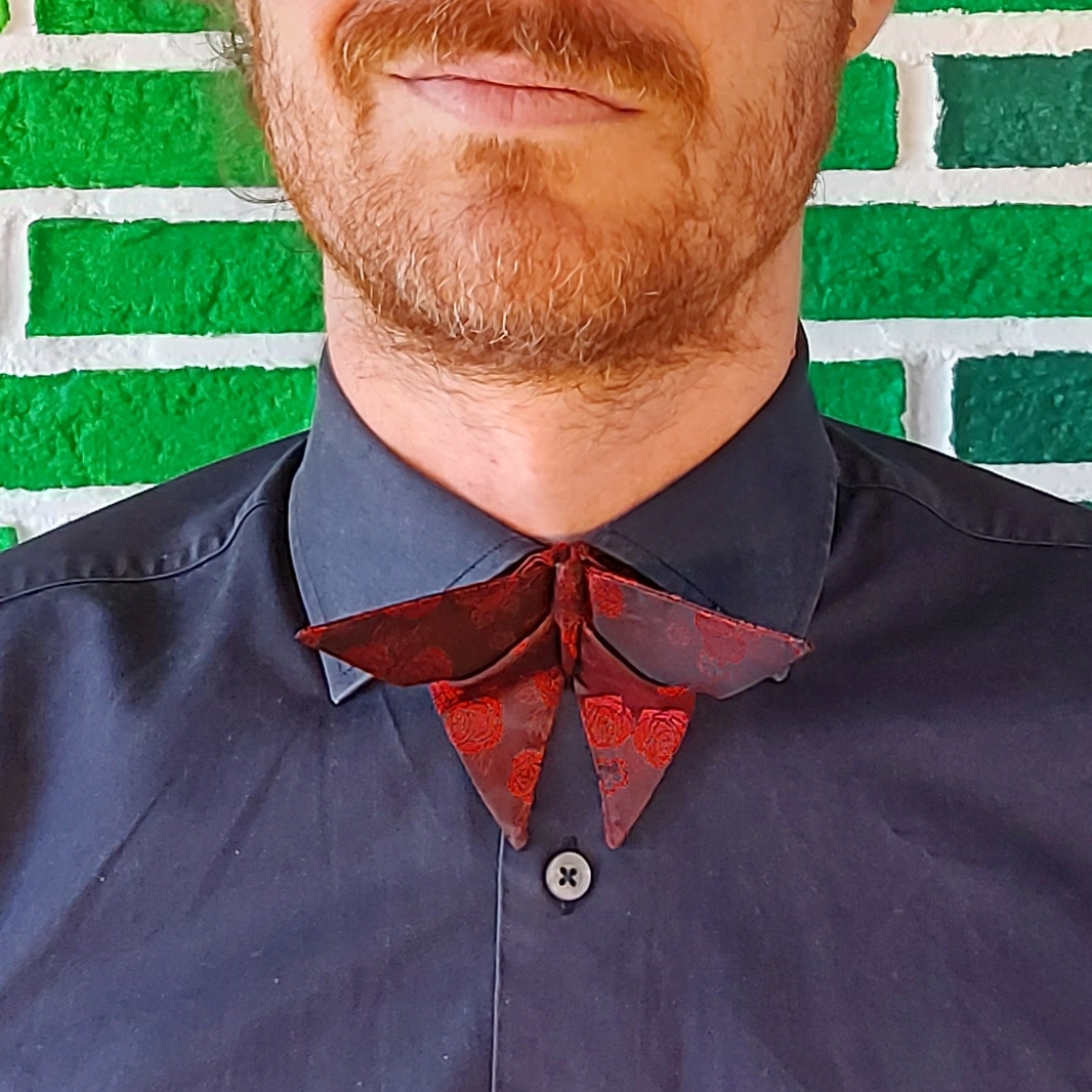 Ginger man with a bark blue shirt and a butterfly bow tie of red roses