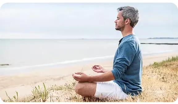 Man sitting on a beach meditating
