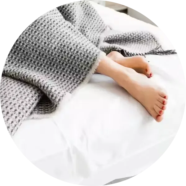 Feet under grey blanket in bed