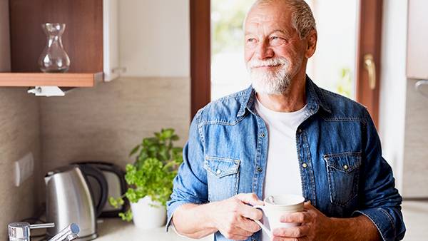 Older man standing in the kitchen with a mug in his hands 