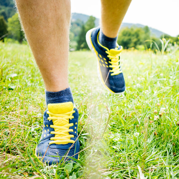man walking through grass in colorful sneakers