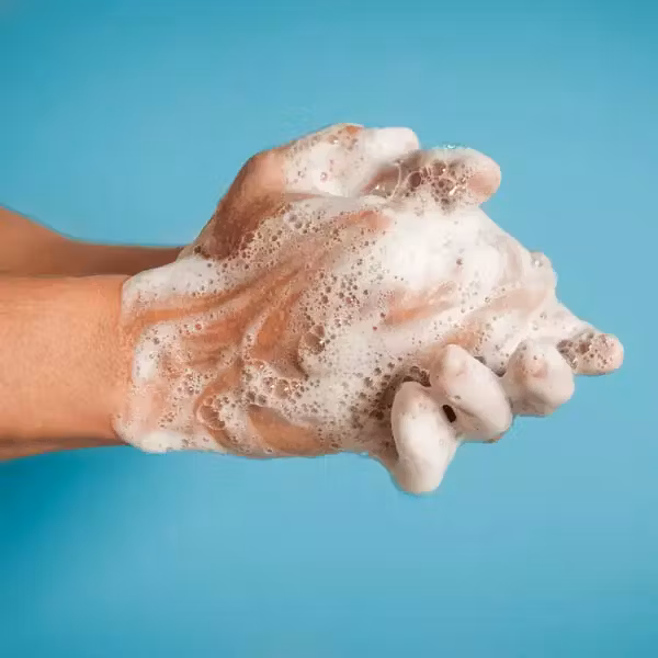 Close-up of person washing hands against blue background