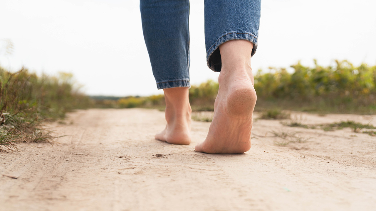 Eine Person geht auf Sand in den Dühnen spazieren.