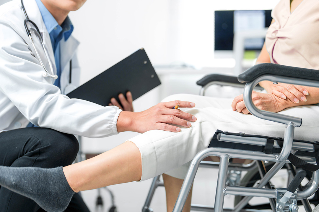 Eine Rollstuhlfahrerin lässt sich von einem Arzt beraten.