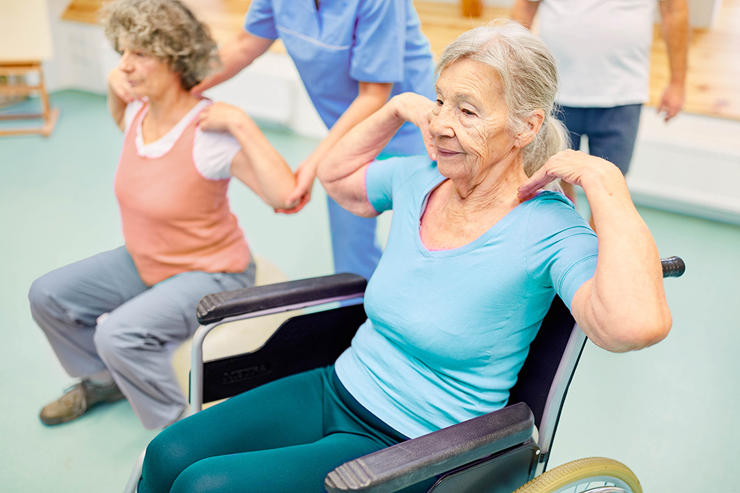 Seniorin im Rollstuhl mach Übungen zum Training.