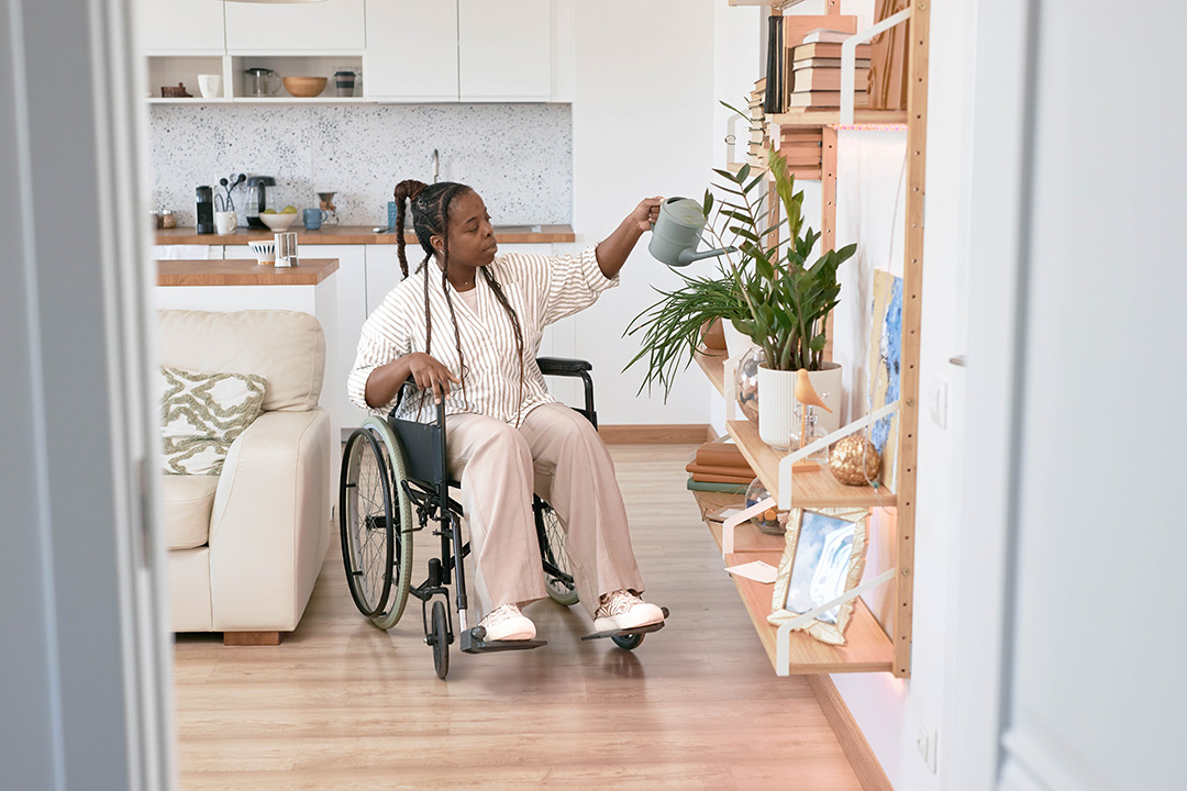 Rollstuhlfahrerin die ihre Zimmerpflanzen pflegt