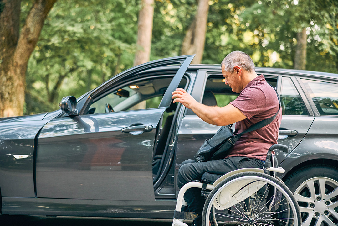 Rollstuhlfahrer steigt selbständig ins Auto um.